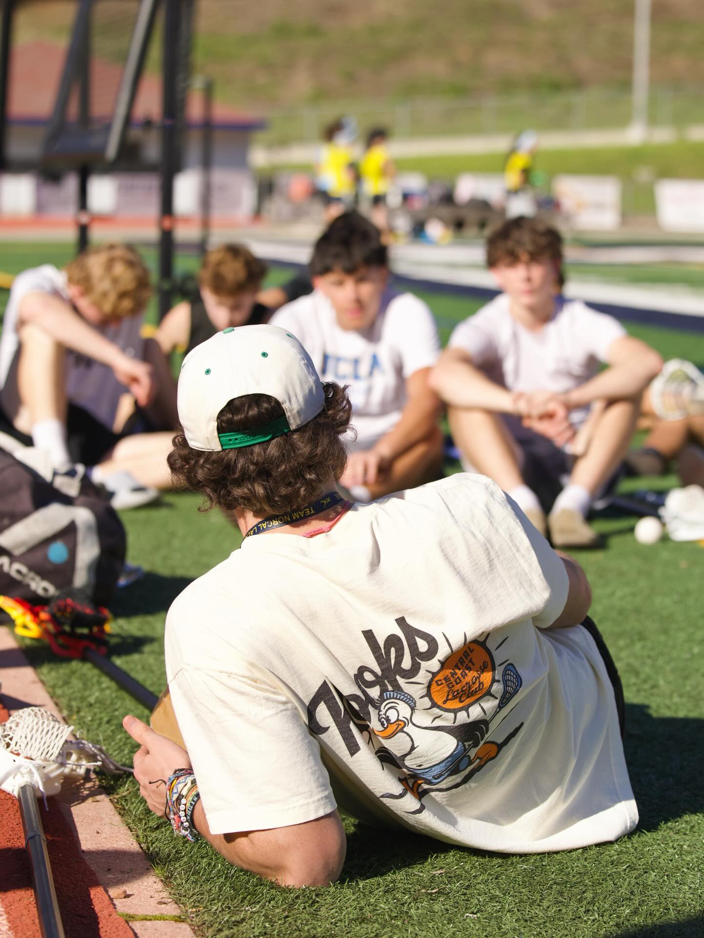 Aidan Niklaus sitting on the grass with youth players at Kooks LC clinic